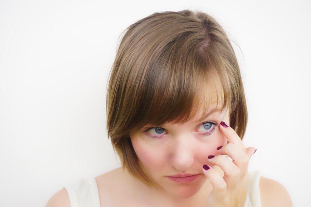 Close Up Young Woman Looking Away While Touching Her Face Against White Background
